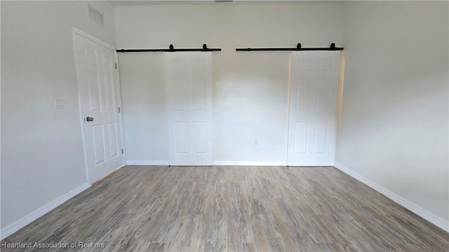 spare room with a barn door and hardwood / wood-style floors