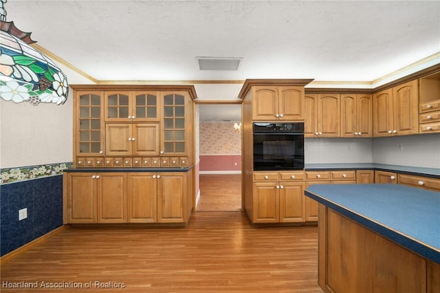 302 S Egret St, Sebring, FL 33870 - kitchen with oven, wallpapered walls, light wood-style floors, dark countertops, and a wainscoted wall