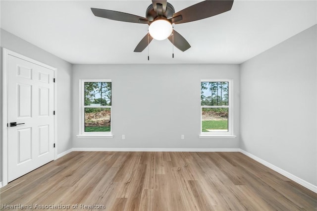 unfurnished room with plenty of natural light, ceiling fan, and light wood-type flooring