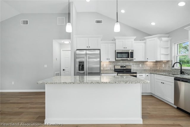 kitchen with appliances with stainless steel finishes, backsplash, sink, pendant lighting, and white cabinetry