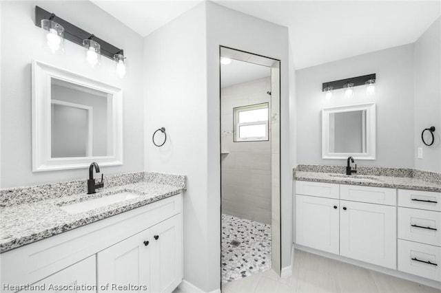 bathroom with a tile shower and vanity