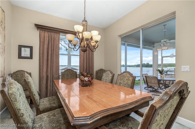 dining area featuring a water view and ceiling fan with notable chandelier