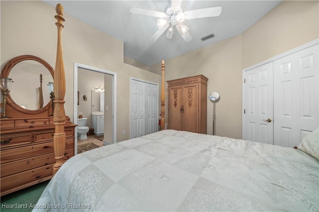 bedroom with connected bathroom, two closets, carpet floors, and ceiling fan