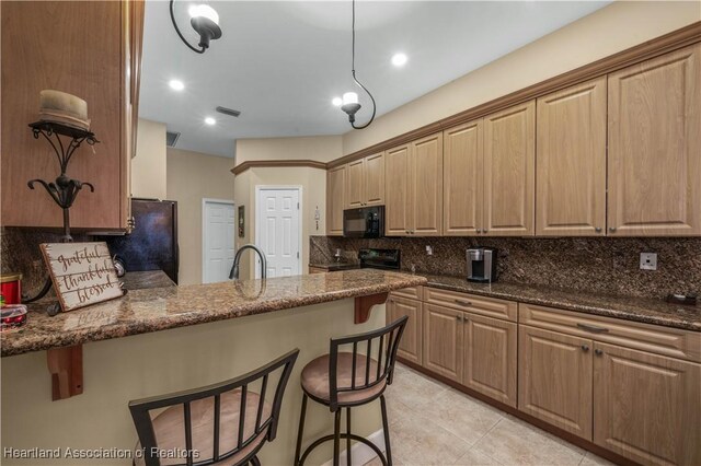 kitchen with sink, black appliances, dark stone countertops, pendant lighting, and backsplash