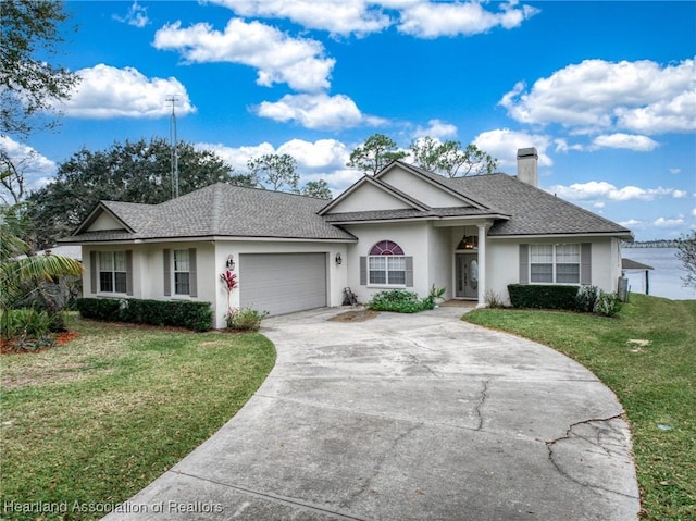 single story home with a garage, a water view, and a front lawn