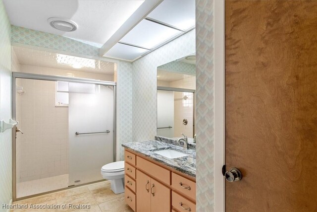 full bath featuring vanity, toilet, wallpapered walls, tile patterned floors, and a tile shower