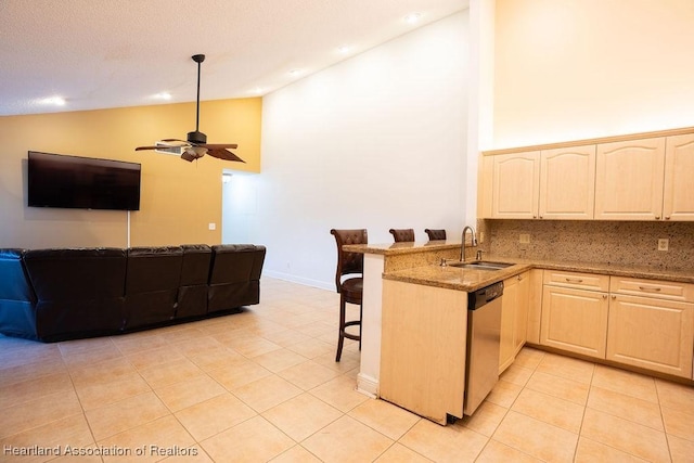 kitchen featuring dishwasher, sink, a kitchen breakfast bar, kitchen peninsula, and light tile patterned floors