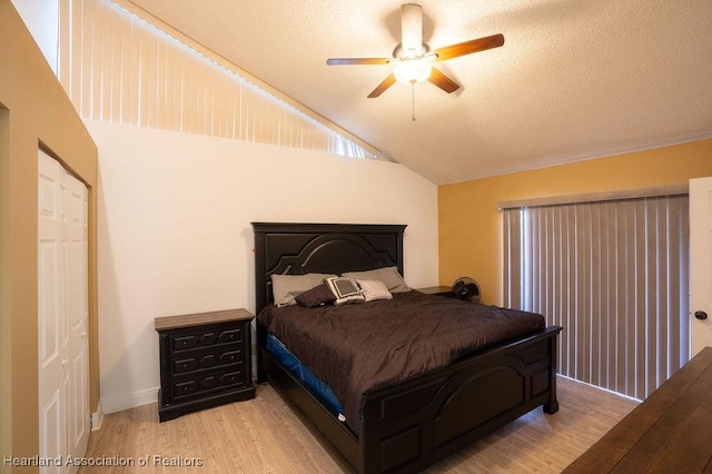 bedroom with a textured ceiling, light hardwood / wood-style floors, vaulted ceiling, and ceiling fan