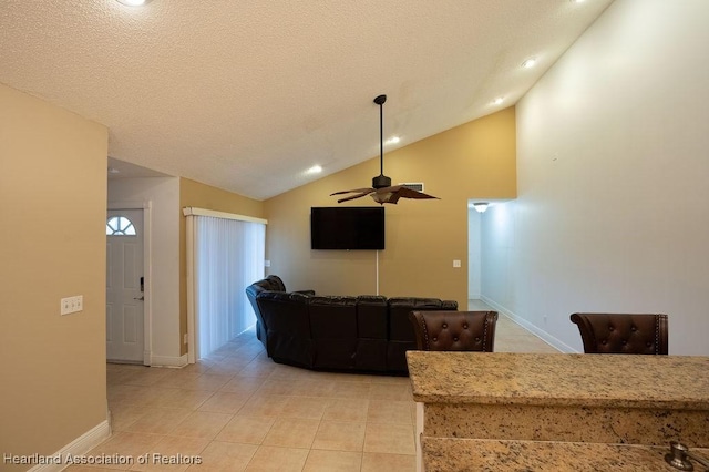 tiled living room featuring ceiling fan, lofted ceiling, and a textured ceiling