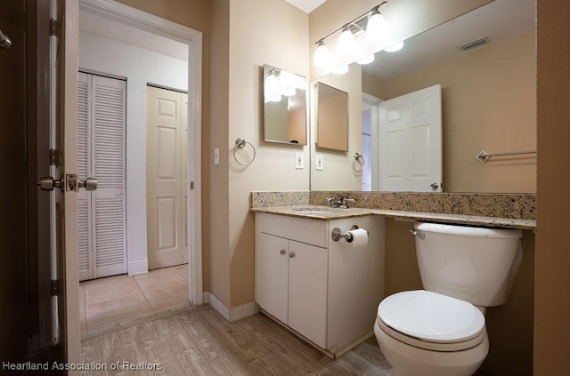 bathroom with toilet, vanity, and hardwood / wood-style flooring