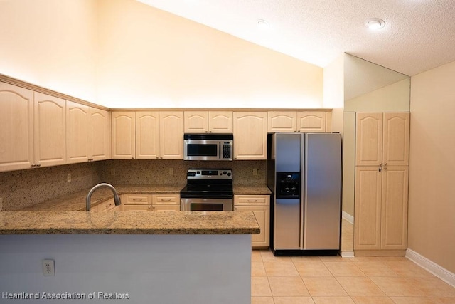 kitchen with light tile patterned flooring, kitchen peninsula, sink, and appliances with stainless steel finishes