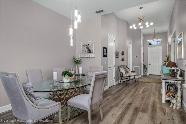 dining area featuring an inviting chandelier, hardwood / wood-style floors, and a towering ceiling