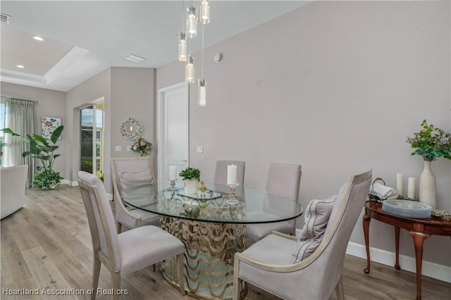 dining area featuring a tray ceiling and light hardwood / wood-style flooring