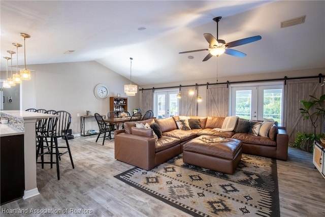 living room with a healthy amount of sunlight, a barn door, visible vents, and lofted ceiling