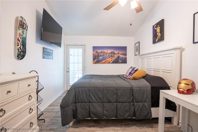 bedroom featuring baseboards, a ceiling fan, lofted ceiling, wood finished floors, and access to exterior