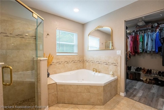 full bathroom featuring tile patterned flooring, a walk in closet, a garden tub, and a shower stall