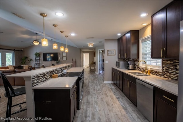 kitchen featuring appliances with stainless steel finishes, open floor plan, a sink, and light countertops