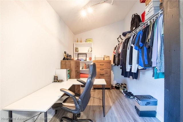 home office featuring lofted ceiling, track lighting, and wood finished floors