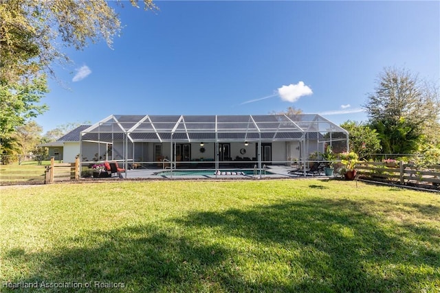 rear view of property featuring a yard, fence, glass enclosure, and an outdoor pool