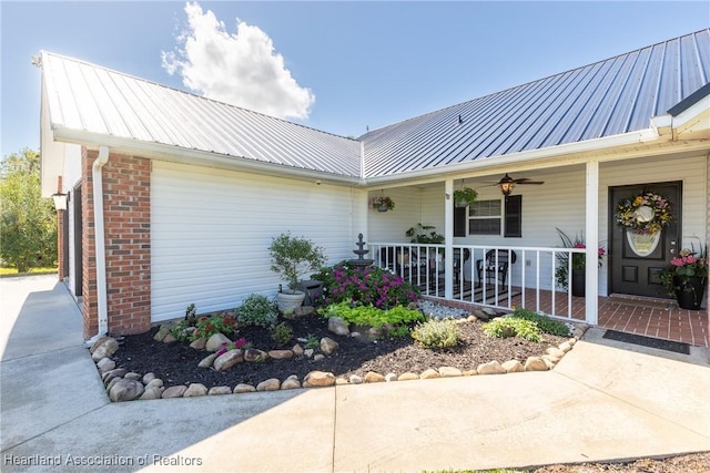 property entrance featuring covered porch, brick siding, and metal roof