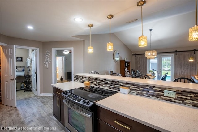 kitchen featuring dark brown cabinetry, a barn door, tasteful backsplash, electric range oven, and lofted ceiling