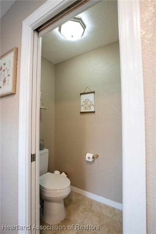 bathroom featuring baseboards, toilet, and tile patterned floors