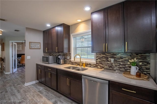 kitchen featuring a sink, light wood-style floors, dark brown cabinets, appliances with stainless steel finishes, and backsplash