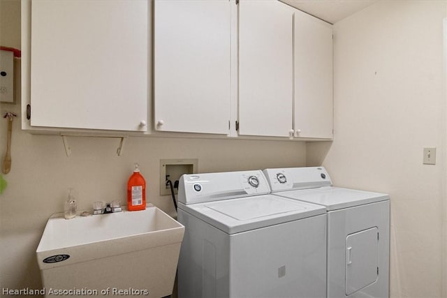 laundry area with washing machine and clothes dryer, cabinets, and sink