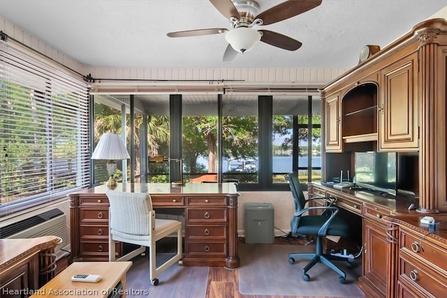 office with dark hardwood / wood-style floors, ceiling fan, and a wall unit AC