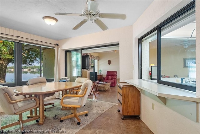 tiled dining area with a wealth of natural light, a water view, and ceiling fan