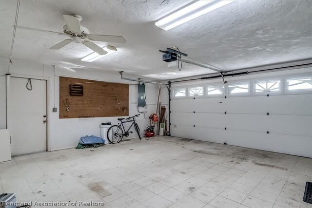 garage featuring electric panel, ceiling fan, and a garage door opener