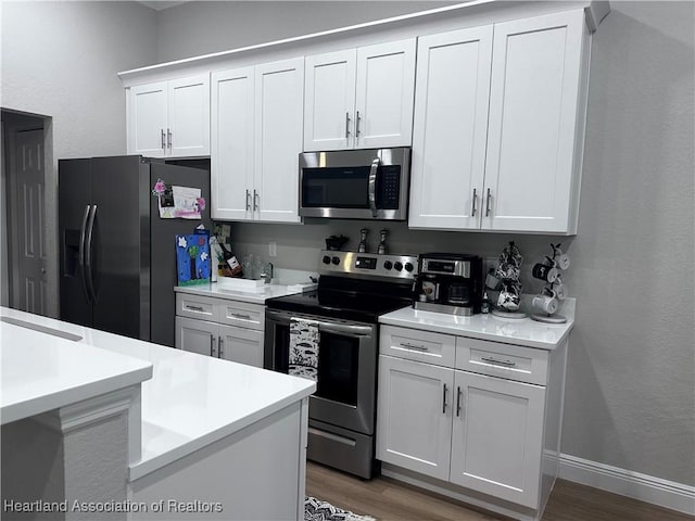 kitchen featuring dark hardwood / wood-style flooring, white cabinets, and appliances with stainless steel finishes