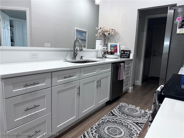 kitchen with appliances with stainless steel finishes, dark hardwood / wood-style floors, gray cabinets, and sink