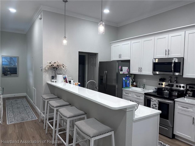 kitchen with white cabinetry, a breakfast bar, decorative light fixtures, and appliances with stainless steel finishes