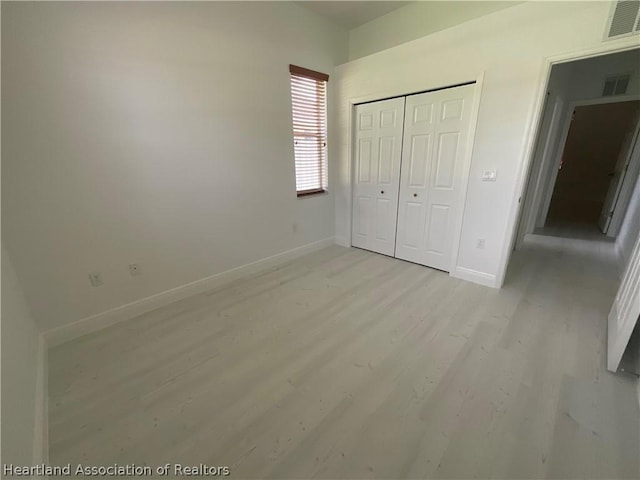 unfurnished bedroom featuring light wood-type flooring and a closet