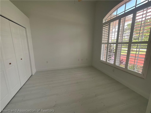 unfurnished bedroom featuring a closet, light wood-type flooring, and multiple windows