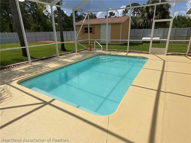 view of swimming pool with a lawn, glass enclosure, a patio, and a storage shed