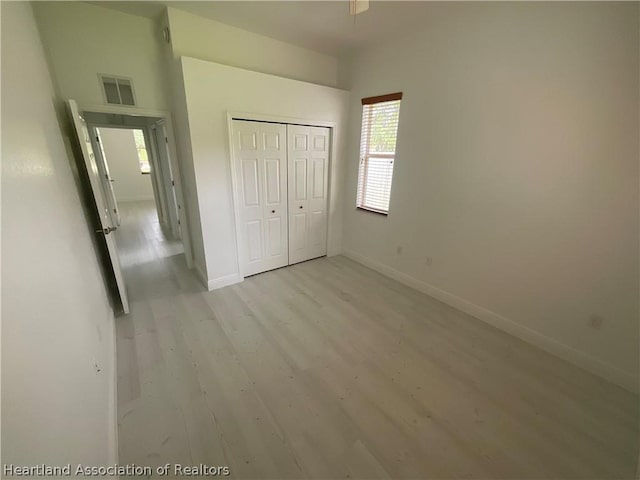 unfurnished bedroom featuring light hardwood / wood-style flooring and a closet