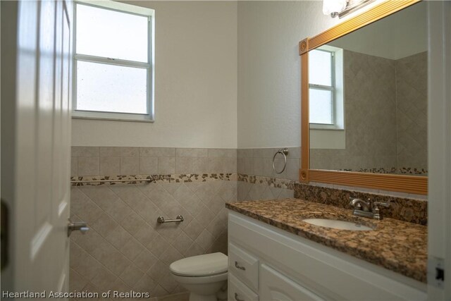 bathroom featuring vanity, tile walls, and toilet