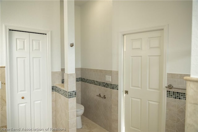 bathroom with tile patterned flooring, tile walls, and toilet