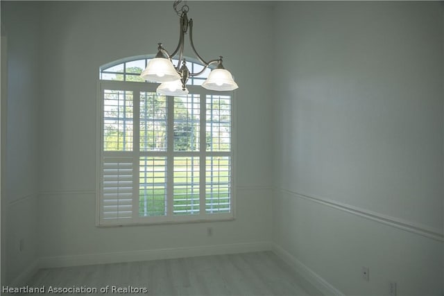 unfurnished room featuring a chandelier and light wood-type flooring