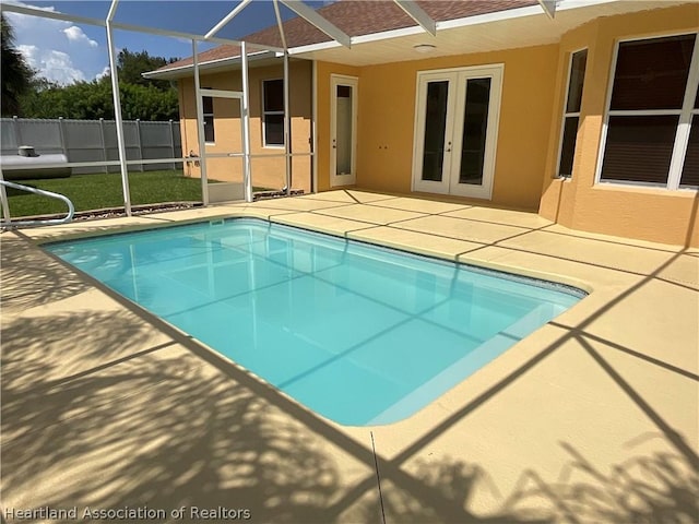 view of pool featuring glass enclosure, a patio, and french doors