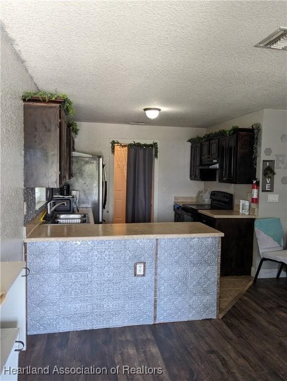 2146 Hartman Rd, Avon Park, FL 33825 - kitchen with black electric range oven, a sink, wood finished floors, freestanding refrigerator, and under cabinet range hood