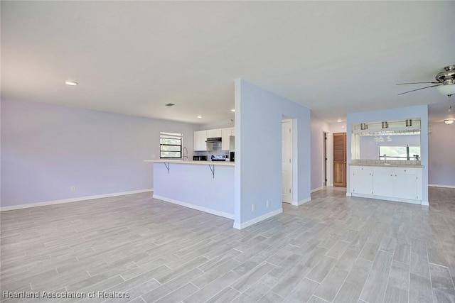 unfurnished living room featuring ceiling fan and light hardwood / wood-style floors