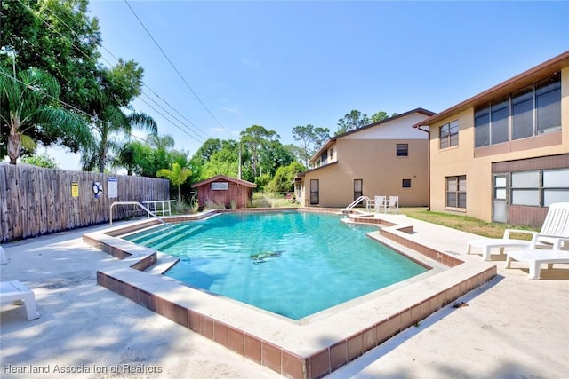 view of swimming pool with a storage shed and a patio