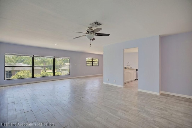 empty room featuring ceiling fan, sink, plenty of natural light, and light wood-type flooring