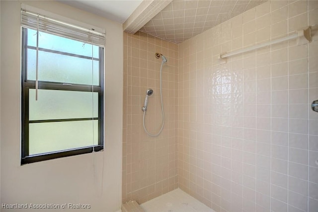 bathroom featuring tiled shower and beamed ceiling