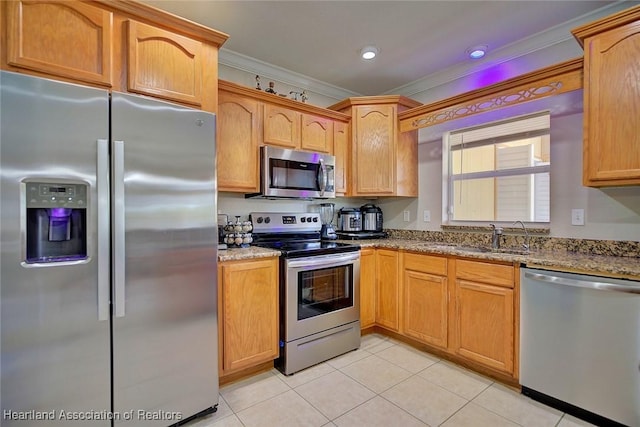 kitchen with sink, crown molding, light tile patterned floors, appliances with stainless steel finishes, and light stone countertops