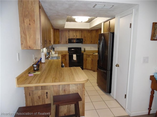 1605 Lake Clay Dr, Lake Placid, FL 33852 - kitchen featuring black appliances, light countertops, a peninsula, brown cabinetry, and light tile patterned floors