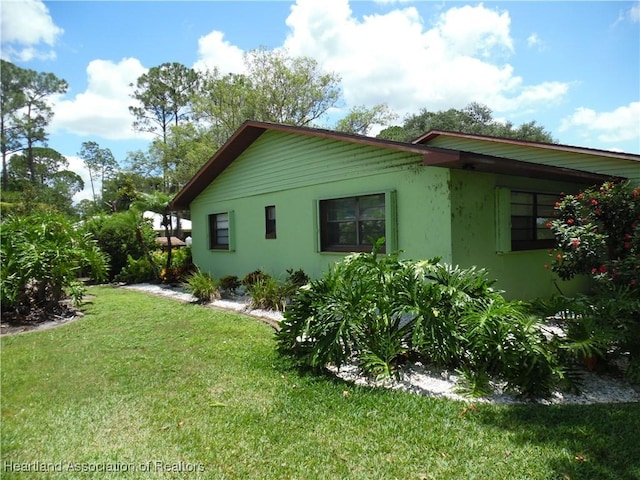 1605 Lake Clay Dr, Lake Placid, FL 33852 - view of side of home featuring stucco siding and a lawn